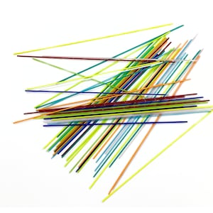 May include: A collection of colorful glass rods in various shades of blue, green, yellow, orange, red, and white. The rods are arranged in a random pattern on a white background.
