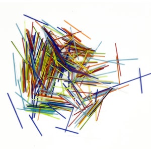 May include: A pile of colorful glass rods in various shades of blue, red, yellow, and green. The rods are scattered on a white background.