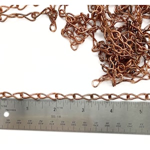 May include: A close-up of a copper chain with a ruler underneath. The ruler is marked in inches and shows the chain is about 5 inches long.