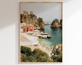 May include: A photograph of a coastal town in Italy. The image shows a pink building with a white awning, a rocky cliffside, and a turquoise blue sea. There are people on the beach and boats in the water.