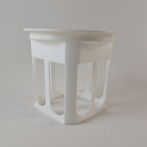 Pode incluir: Um vaso de plantas de plástico branco com uma borda superior quadrada e uma estrutura de armação aberta com quatro pilares de suporte verticais e uma base sólida. O design inclui grandes aberturas retangulares em cada lado.