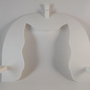 May include: A white, abstract wall shelf with a unique, arched design. The shelf features two curved side panels and a central support, with two small rectangular extensions at the base. The overall shape is reminiscent of a stylized architectural element.