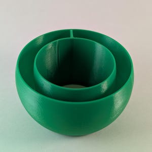 Könnte beinhalten: Ein grüner Plastikring mit drei konzentrischen Kreisen. Der Ring ist hohl und hat eine glatte Oberfläche.