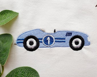 Pode incluir: Carro de corrida azul bordado com pneus pretos e um número 1 branco em um círculo azul. O carro tem um fundo branco e o número 101 é bordado no lado.