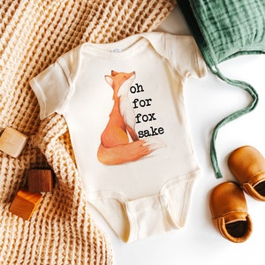 Könnte beinhalten: Ein weißer Baby-Strampler mit einer Fuchs-Illustration und dem Text "oh for fox sake".