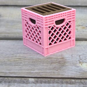 May include: A pink plastic crate with a brown top and six slots. The crate is made of a lattice design.