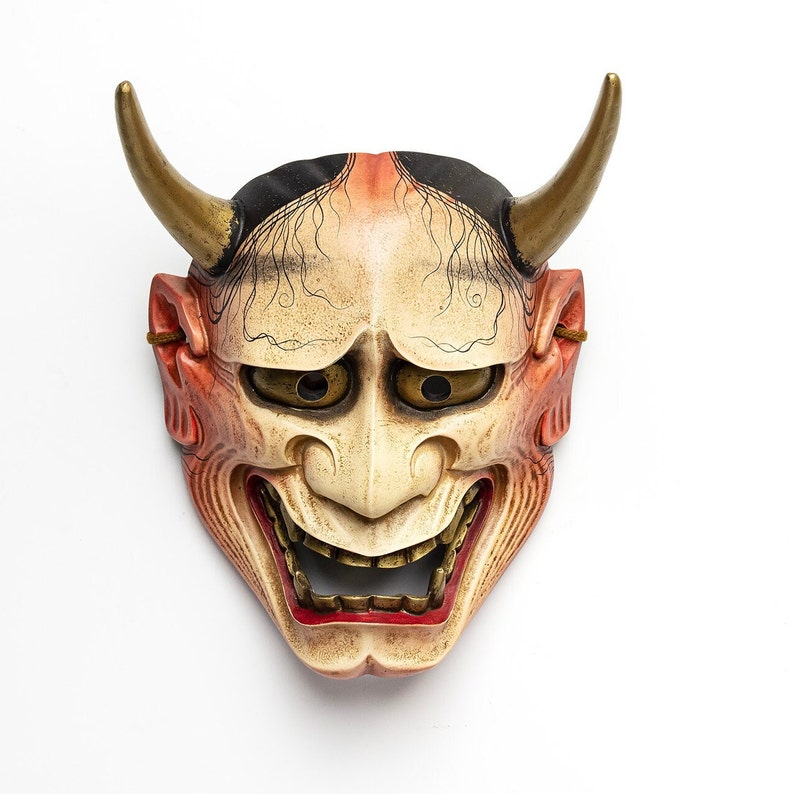 May include: A traditional Japanese demon mask with red and white paint, black eyes, and gold horns. The mask has a wide, toothy grin.
