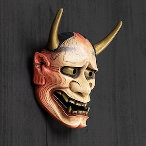 May include: A traditional Japanese demon mask with red, white, and black paint. The mask has horns and a fierce expression.