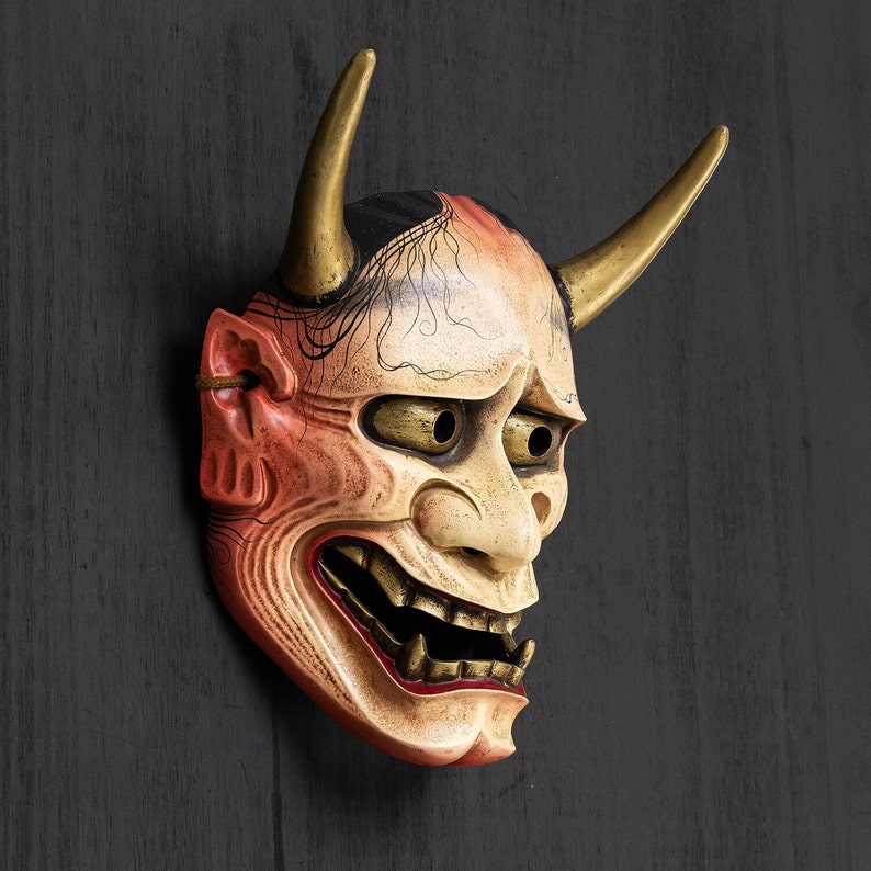 May include: A traditional Japanese demon mask with red, white, and black paint. The mask has horns and a fierce expression.