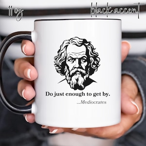May include: White ceramic mug with a black handle and rim. The mug features a black and white illustration of a man with a beard and the text "Do just enough to get by...Mediocrates".