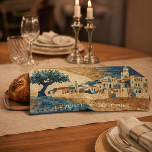 Könnte beinhalten: Ein Challah-Brot, eingewickelt in ein dekoratives Tuch mit einem Mosaikdesign eines Baumes und eines Dorfes mit blauen Dächern. Die Szene spielt sich auf einem Tisch mit Kerzen, Glaswaren und Silberwaren ab.