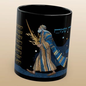 Puede incluir: Taza de cerámica negra con una ilustración de una figura vestida con una túnica que lleva trigo. La figura camina con un bastón, sobre un cielo estrellado. Texto hebreo visible en la taza.