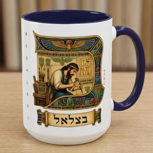 Könnte beinhalten: Weißer Keramikbecher mit marineblauem Innenraum und Henkel. Der Becher zeigt eine Illustration eines Mannes, der mit Werkzeugen arbeitet, umgeben von Kunst im Hieroglyphenstil. Der Becher hat Text in Hebräisch und Englisch.