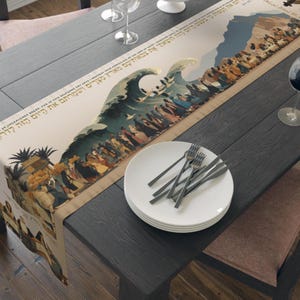 May include: A beige table runner with a detailed illustration of a biblical scene, featuring a large wave and figures. The runner is placed on a dark gray wooden table, with white plates and silverware.