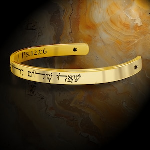 May include: Gold bracelet with a Hebrew inscription and the text "Ps.122:6" on the band. The bracelet has two small stars on either side of the inscription.