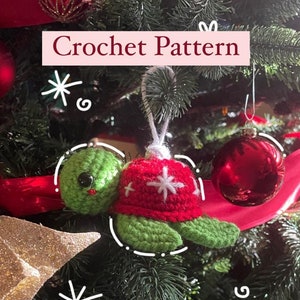 May include: Crocheted turtle ornament with a red and white snowflake pattern. The ornament is hanging on a Christmas tree.