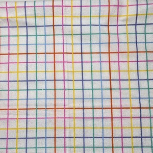 May include: White fabric with a colorful grid pattern. The grid lines are in various colors, including red, blue, green, yellow, and purple. The fabric appears to be soft and possibly cotton or linen.