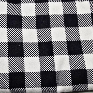 May include: Close-up of a black and white checkered fabric. The pattern consists of alternating squares of solid black and white, with diagonal lines filling some of the black squares. The fabric appears to be soft and possibly used for clothing or home decor.