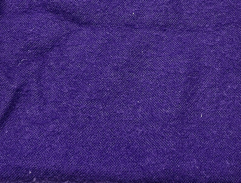 May include: Close-up of a deep purple fabric with a textured, woven appearance. The material has a slightly uneven surface, with subtle variations in color and texture. The fabric appears to be a textile.