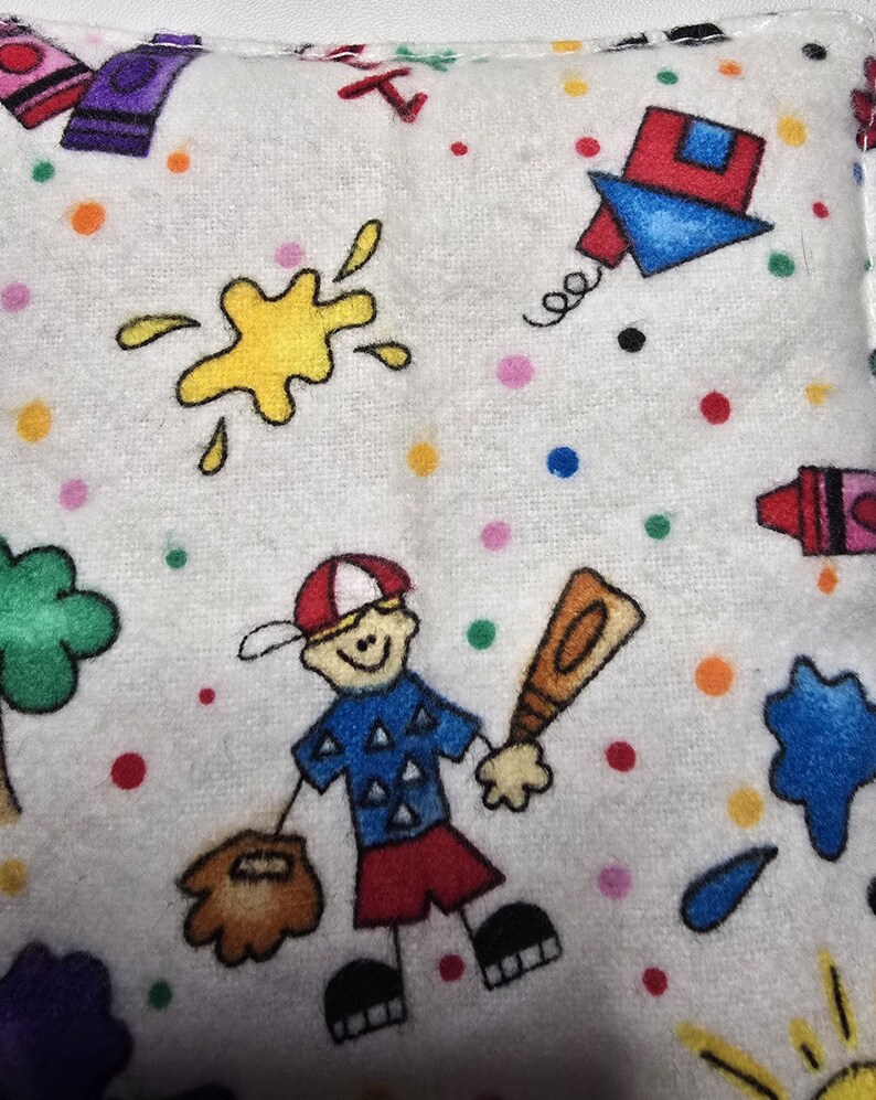 May include: White fabric with colorful illustrations of a baseball player, crayons, paint splatters, and a kite. The design includes a baseball player holding a bat and glove, surrounded by polka dots.