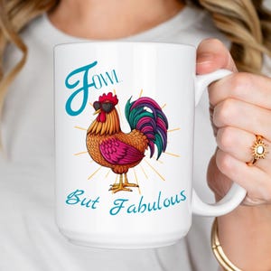 Puede incluir: Taza de cerámica blanca con un gallo colorido con gafas de sol en forma de corazón. La taza tiene el texto "Jowl But Fabulous" en escritura turquesa. El gallo tiene una cresta roja, cuerpo naranja y una vibrante cola morada y verde.