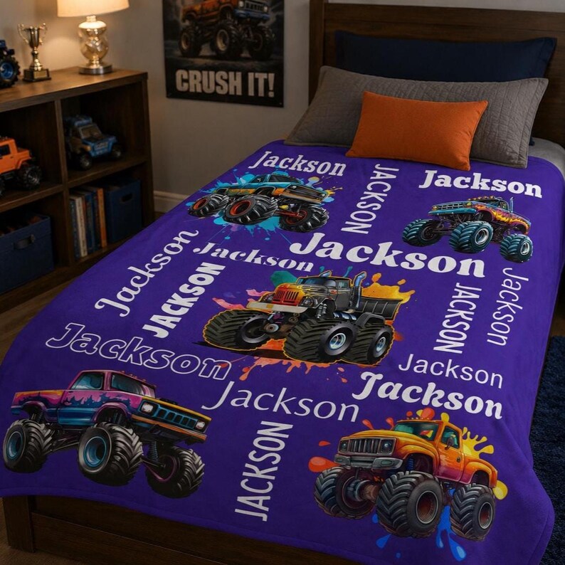 Op de afbeelding: Een paarse fleece deken met illustraties van kleurrijke monstertrucks en de naam "Jackson" in het wit. De deken heeft een herhalend patroon van monstertrucks en de naam "Jackson".