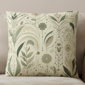 May include: A square throw pillow featuring a cream-colored background with a repeating botanical pattern in shades of sage green, olive, and soft peach. The design includes stylized leaves, flowers, and delicate dotted lines and circles.