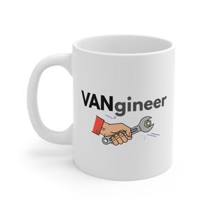 May include: White ceramic mug with the word "VANgineer" in black text. An illustration of a hand holding a wrench is below the text. The wrench is tightening a nut. The mug has a curved handle.