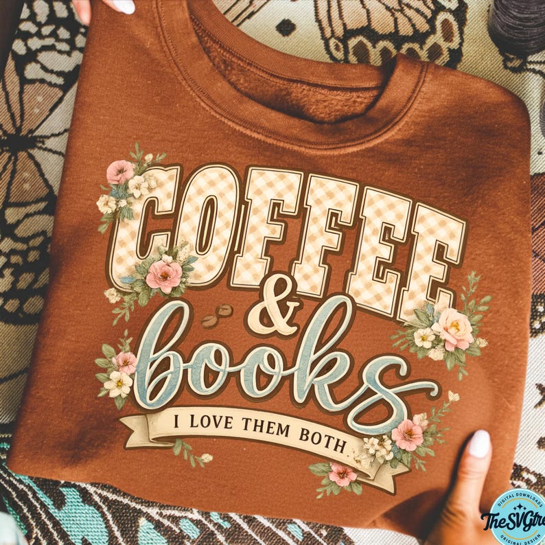 Op de afbeelding: Een bruine sweatshirt met de tekst "COFFEE & books" in een decoratief lettertype, met bloemaccenten. De tekst "I LOVE THEM BOTH" staat eronder. Het ontwerp bevat koffiebonen en bloemen.