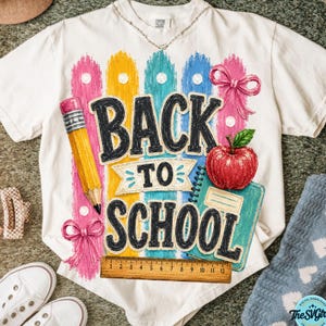 Peut inclure: Un t-shirt blanc avec un motif coloré portant l'inscription BACK TO SCHOOL, un crayon jaune, une pomme rouge et des nœuds roses. Une règle en bois est placée en bas du motif, affichant des mesures en centimètres de 0 à 12.