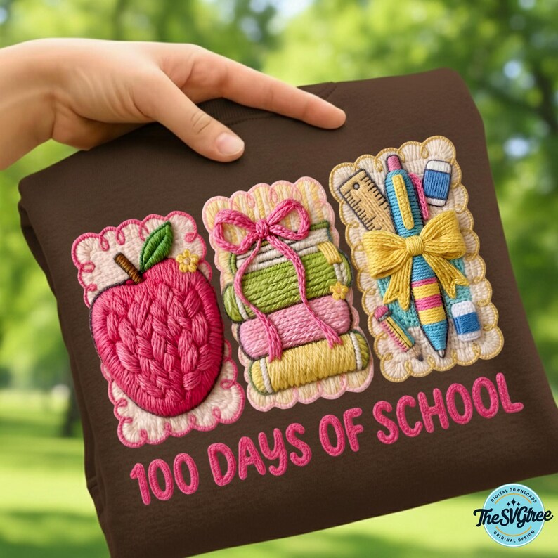Pu&ograve; includere: Una felpa marrone con ricami a tema scolastico. Il design include una mela rosa, libri impilati e materiale scolastico. Il testo "100 DAYS OF SCHOOL" &egrave; ricamato in rosa. Il design &egrave; incorniciato da un bordo smerlato.