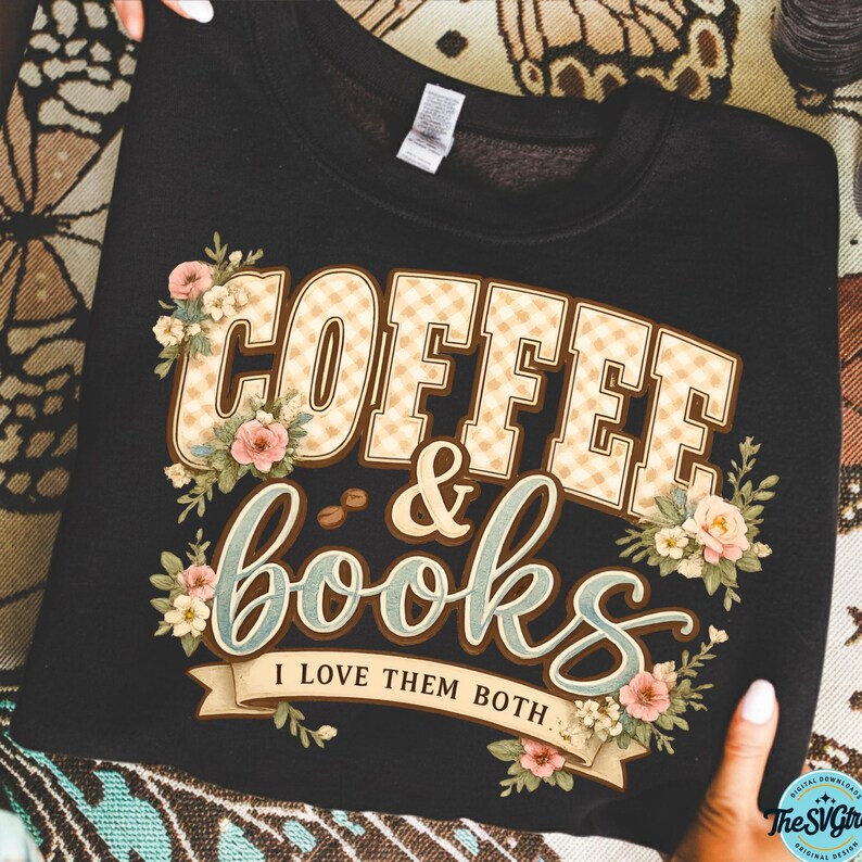 Op de afbeelding: Zwart sweatshirt met de tekst "COFFEE & books" in een geruit patroon, bloemversieringen en de zin "I LOVE THEM BOTH". Het ontwerp bevat koffiebonen en pastelkleurige bloemen.