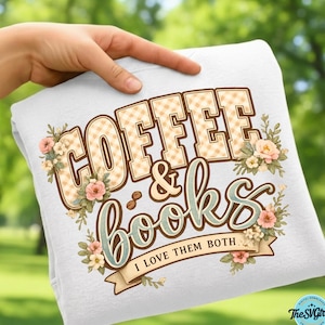 Op de afbeelding: Witte sweatshirt met de woorden "COFFEE & BOOKS" in een decoratief lettertype, met bloemaccenten. De tekst "I LOVE THEM BOTH" staat op een banner eronder. De letters in "COFFEE" hebben een ruitpatroon.