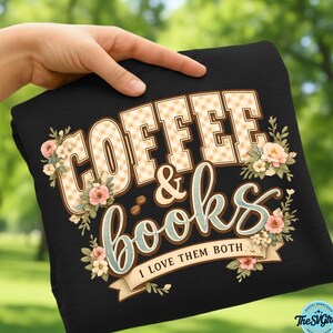Op de afbeelding: Zwart sweatshirt met de tekst "COFFEE & books" in een decoratief lettertype, met bloemaccenten. De tekst "I LOVE THEM BOTH" staat op een banner eronder. De letters hebben een ruitpatroon.