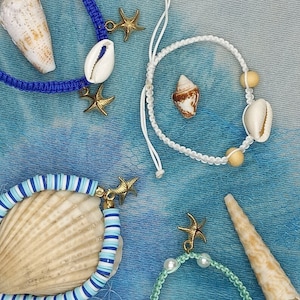 May include: Four handmade bracelets with seashell charms and starfish accents. The bracelets are made with blue, white, and green cord. The charms are made of natural seashells and gold-toned metal.