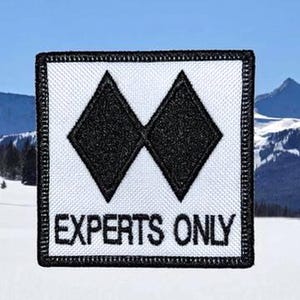 May include: A square embroidered patch with a white background and a black border. The design features two black diamond shapes side by side above the text "EXPERTS ONLY" in black capital letters, mimicking a ski trail difficulty sign.