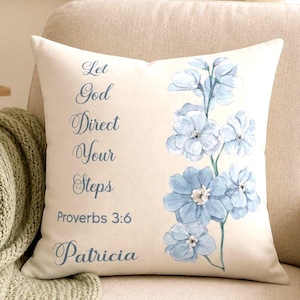 May include: Cream-colored square throw pillow with blue floral design and script text. The text reads "Let God Direct Your Steps Proverbs 3:6 Patricia". The pillow is on a beige armchair.
