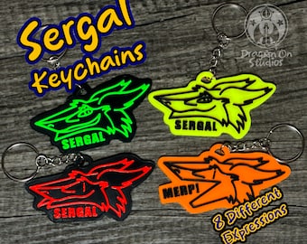 May include: Four different colored keychains featuring a cartoon Sergal with different expressions. The keychains are black, green, orange, and yellow. The text "Sergal Keychains" is in the top left corner of the image. The text "8 Different Expressions" is in the bottom right corner of the image.