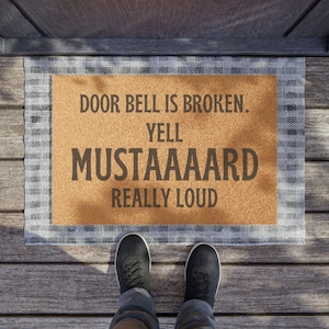 May include: A brown doormat with white trim and the text "Door bell is broken. Yell MUSTAAARD really loud".