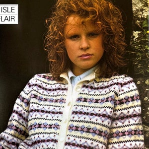 Puede incluir: Un cárdigan blanco con un patrón geométrico colorido. El cárdigan tiene un cierre de botones y mangas largas. La modelo lleva una camisa blanca debajo del cárdigan.