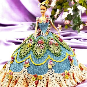 May include: A crocheted doll dress with a blue bodice and a multi-colored floral design. The dress has a full skirt with layers of crocheted lace.