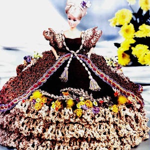 May include: A crocheted doll dress with a brown bodice, a beige skirt with multiple layers of ruffles, and a purple and gold trim. The doll is wearing a pearl necklace and has blonde hair with a purple flower.