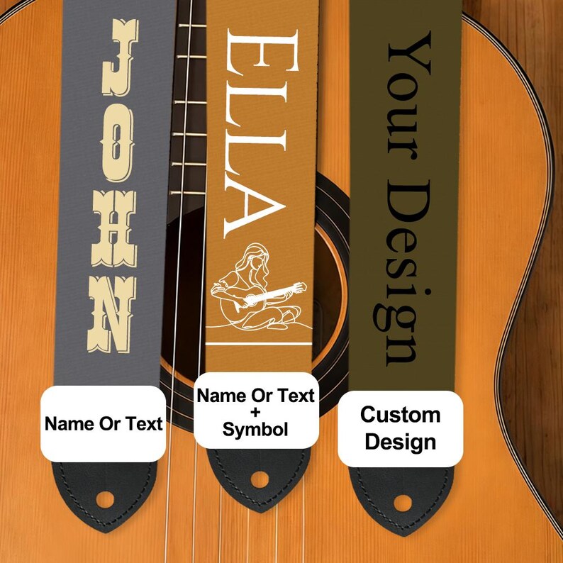 May include: Three guitar straps with different designs are displayed against a wooden acoustic guitar. One strap is gray with the name "JOHN" in a serif font. Another is tan with the name "ELLA" and a guitar player illustration. The third is olive green with "Your Design".