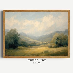 May include: A framed landscape painting with a serene countryside scene. The artwork features a field of yellow and green grass, rolling hills, trees, and a cloudy sky. The frame is made of light brown wood. Text at the bottom reads "Printable Prints CANADA".