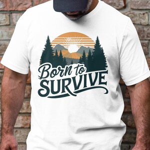 Könnte beinhalten: Weißes T-Shirt mit einer Grafik eines Sonnenuntergangs hinter einem Wald mit dem Text "Born to Survive" in einer stilisierten Schrift.