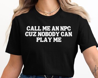 May include: Black t-shirt with white text that reads "CALL ME AN NPC CUZ NOBODY CAN PLAY ME"