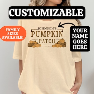 Pode incluir: Uma camiseta bege com um gráfico marrom de abóboras e o texto "Johnson's Pumpkin Patch". O texto "Your Name Goes Here" também está na camiseta.