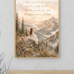 May include: A framed art print featuring a serene mountain landscape with a woman in a white dress. The artwork includes the text "I lift up my eyes to the mountains" and "Psalm 121:1". The color palette includes soft blues, greens, and warm earth tones.