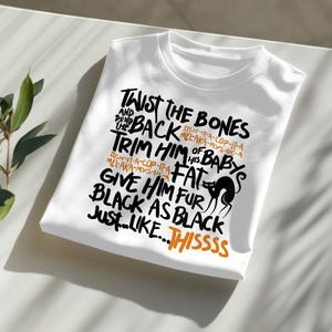 K&ouml;nnte beinhalten: Wei&szlig;es T-Shirt mit schwarzem Text, der "Twist the bones and back, trim him of his baby's fat, give him fur black as black just like...thissss" lautet. Der Text ist handschriftlich. Eine schwarze Silhouette einer Katze ist im Text enthalten.