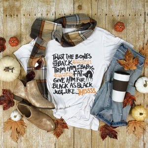 K&ouml;nnte beinhalten: Wei&szlig;es T-Shirt mit schwarzem Text, der lautet: "Twist the bones and bend the back of baby's trim him fat give him fur black as black just like thissss".